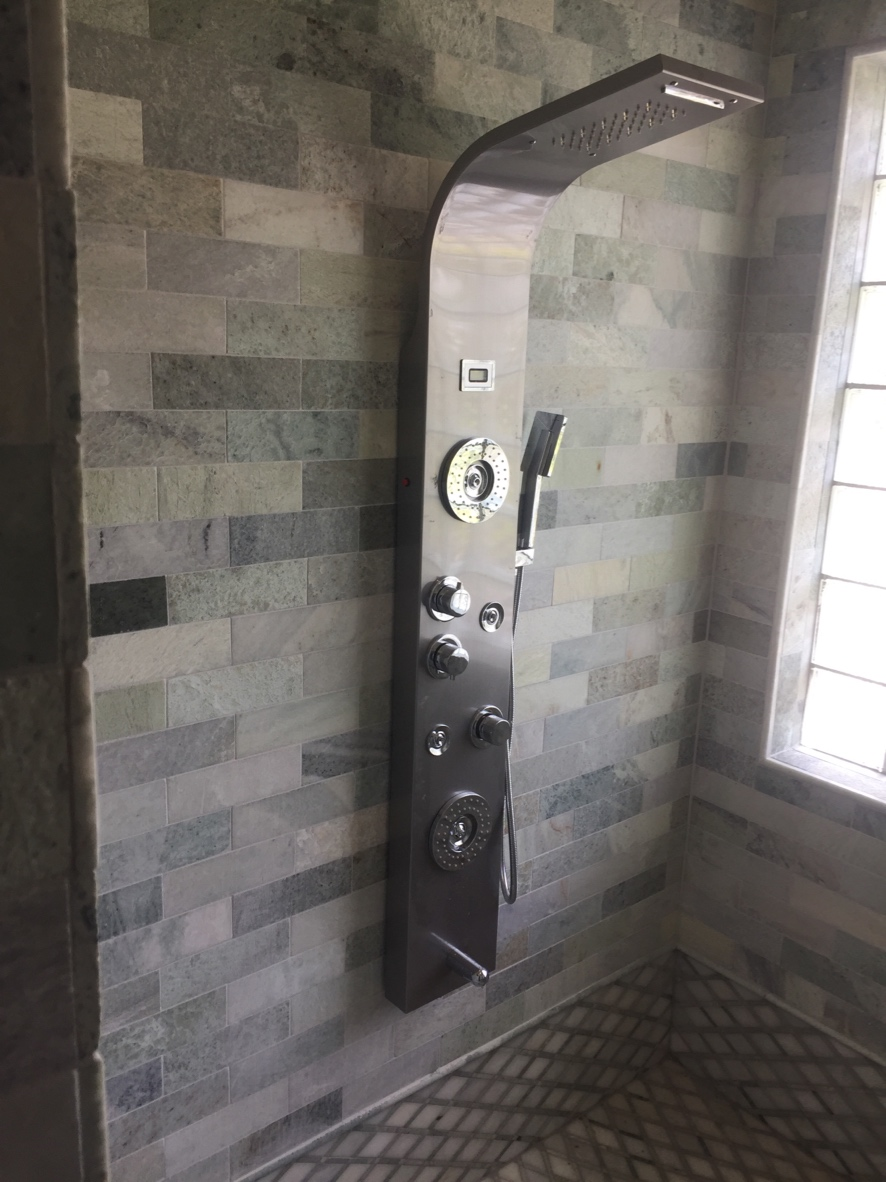 Stainless shower tower panel installed on stone tile wall