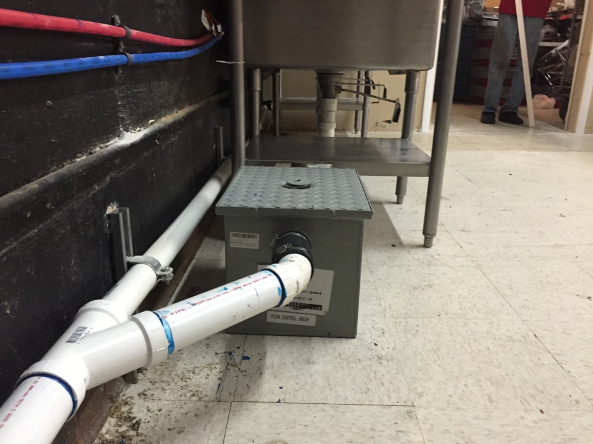 Under-sink grease trap installed in a commercial kitchen