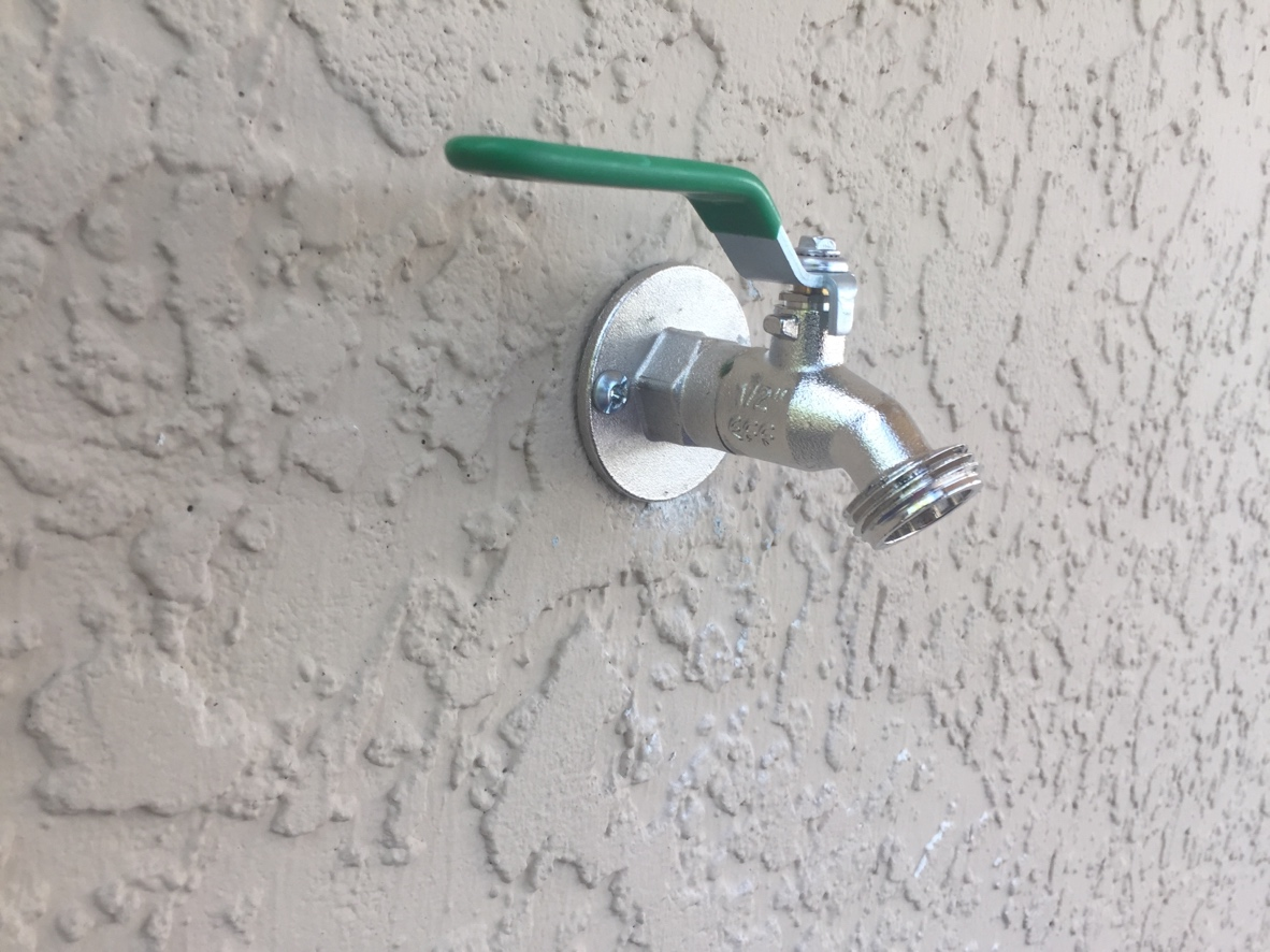 New quarter-turn hose bib installed on a stucco exterior wall